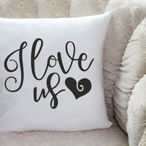 May include: White throw pillow with black cursive text that reads "I love us" and a black heart with a swirl design.