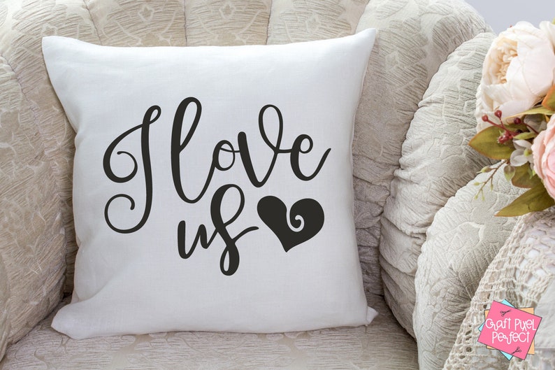 May include: White throw pillow with black cursive text that reads "I love us" and a black heart with a swirl design.