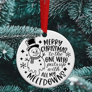 Puede incluir: Adorno navide&ntilde;o blanco con una ilustraci&oacute;n en blanco y negro de un mu&ntilde;eco de nieve derriti&eacute;ndose. El adorno dice "Feliz Navidad al que aguanta todas mis rabietas".