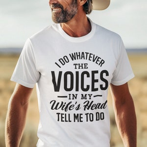 May include: A white t-shirt with a black graphic that says "I do whatever the voices in my wife's head tell me to do".