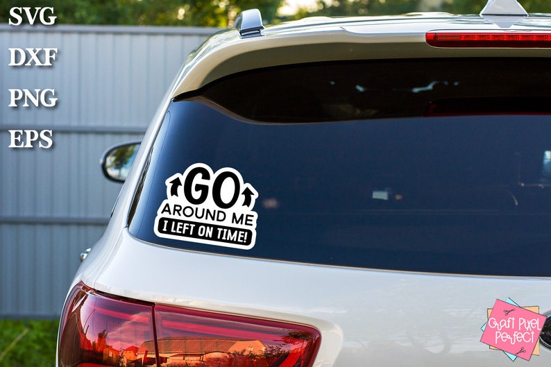 May include: A white car with a black and white sticker on the back window that says "GO AROUND ME I LEFT ON TIME!" with arrows pointing up on either side of the word "GO".