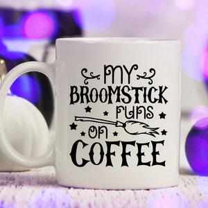 Peut inclure: Une tasse &agrave; caf&eacute; blanche avec du texte noir qui dit "My broomstick runs on coffee" avec une illustration noire et blanche d'un balai et d'&eacute;toiles.