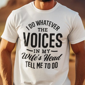 May include: A white t-shirt with black text that reads "I do whatever the voices in my wife's head tell me to do".