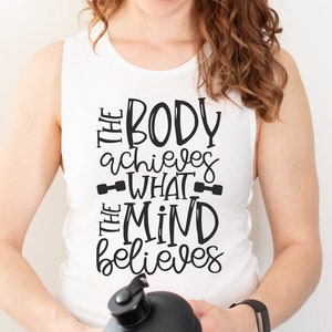 Puede incluir: Un top blanco de tirantes con el texto "The body achieves what the mind believes" en letras negras. El texto est&aacute; estilizado con un gr&aacute;fico de mancuerna a cada lado de la palabra "what".