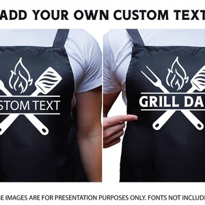 May include: Black apron with a white design of crossed grilling tools, a flame, and the text "CUSTOM TEXT" or "GRILL DAD".