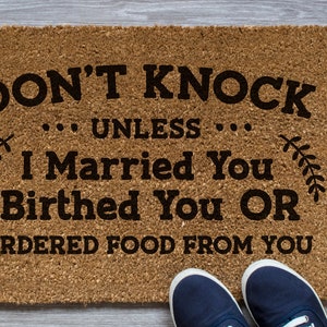 K&ouml;nnte beinhalten: Eine braune Fu&szlig;matte mit dem Text "DON'T KNOCK... UNLESS... I Married You Birthed You OR ORDERED FOOD FROM YOU" in schwarzer Schrift.