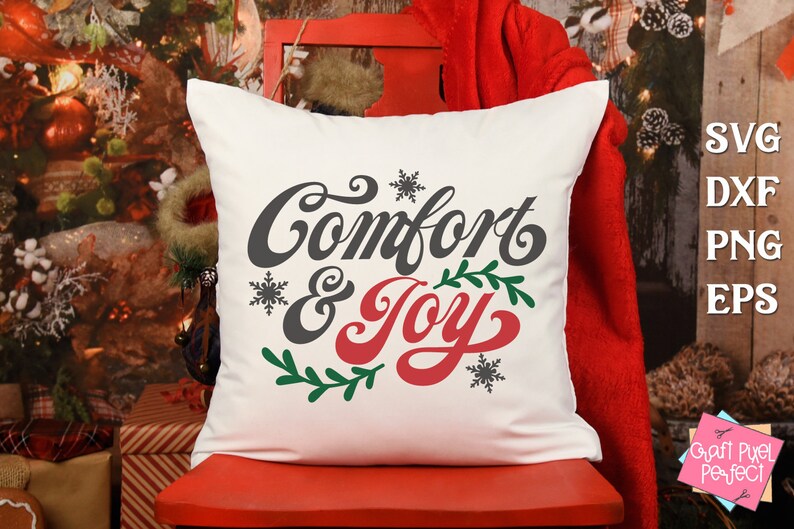 May include: White throw pillow with the text "Comfort & Joy" in a festive font. The text is in gray and red with green leaves and snowflakes.