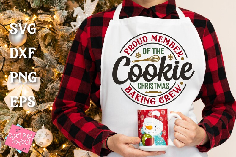 May include: A white apron with the text "Proud Member of the Cookie Christmas Baking Crew" in a red and gold circle. The apron is being worn by a person wearing a red and black plaid shirt.