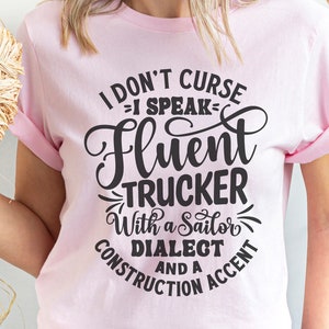 May include: Pink t-shirt with a black graphic that says "I don't curse, I speak fluent trucker with a sailor dialect and a construction accent."