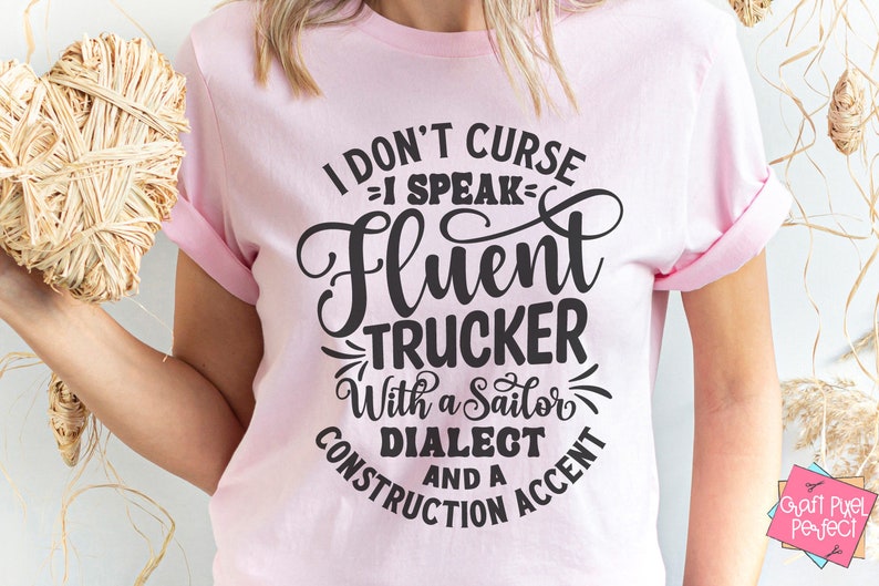 May include: Pink t-shirt with a black graphic that says "I don't curse, I speak fluent trucker with a sailor dialect and a construction accent."