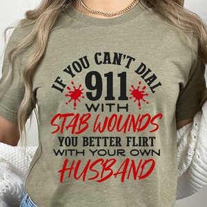 May include: A green t-shirt with the text "If you can't dial 911 with stab wounds you better flirt with your own husband" in black and red lettering.