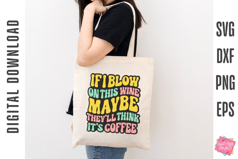Op de afbeelding: Een witte tote bag met de tekst "If I blow on this wine maybe they'll think it's coffee" in kleurrijk retro-lettertype.