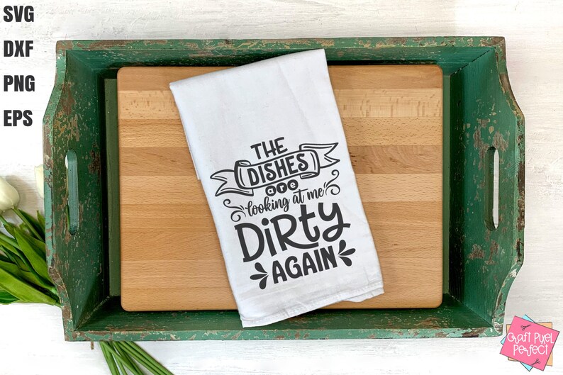 May include: A white kitchen towel with the text "THE DISHES looking at me Dirty AGAIN" in black script. The towel is on a wooden cutting board inside a distressed green tray. The image includes SVG, DXF, PNG, and EPS file type labels.