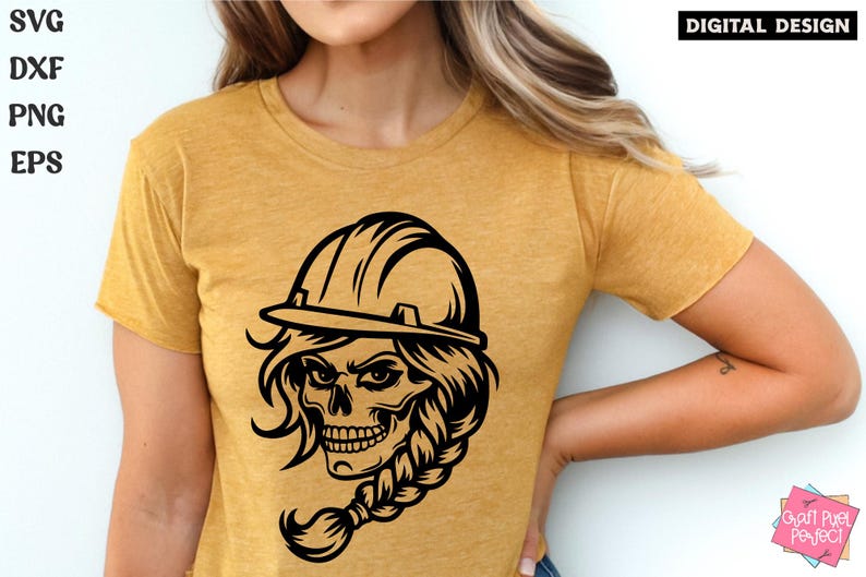 Op de afbeelding: Een zwart-witte illustratie van een schedel die een helm en een vlecht draagt. De schedel heeft een woeste uitdrukking en draagt een helm met een rand. De vlecht is lang en golvend. De illustratie is op een geel T-shirt.