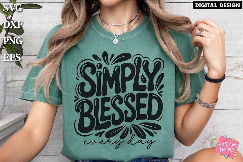 May include: A teal t-shirt with the words "SIMPLY BLESSED" in large, black, stylized letters, with "every day" below. The shirt has a relaxed fit and short sleeves. The words "DIGITAL DESIGN" are in the top right corner.