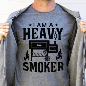 May include: A gray t-shirt with black text that reads "I am a Heavy Smoker" with a black silhouette of a smoker grill and flames below the text.