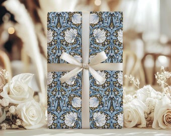 May include: A wrapped gift box with a floral pattern in blue, white, and gold, tied with a cream-colored ribbon. The floral design features stylized flowers and leaves. The gift box is surrounded by white roses.