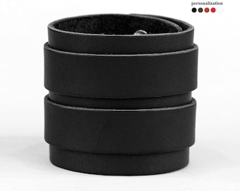 May include: Black leather cuff bracelet with multiple layers of leather. The bracelet is made of a thick, durable leather and has a simple, classic design.