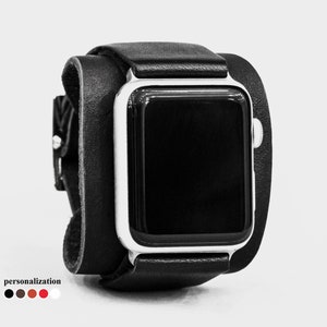 May include: Black leather Apple Watch cuff with a silver watch face. The cuff wraps around the wrist and fastens with a buckle. The word "personalization" is printed at the bottom, with color options.