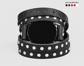 May include: Black leather watch band with silver studs. The band is wrapped around a black watch face.