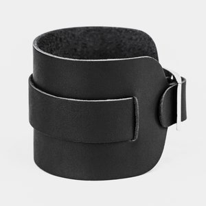 May include: A black leather cuff bracelet with a silver buckle.