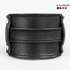 May include: A black leather cuff bracelet with a wide band and two smaller bands. The bracelet is secured with silver-colored rivets. The word "personalization" is above the color options.