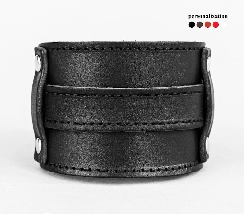 May include: A black leather cuff bracelet with a wide band and two smaller bands. The bracelet is secured with silver-colored rivets. The word "personalization" is above the color options.