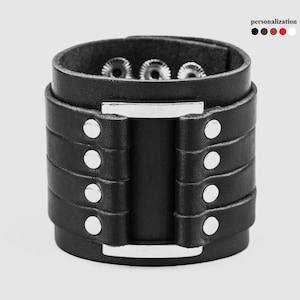May include: Black leather cuff bracelet with silver studs and a silver metal buckle.