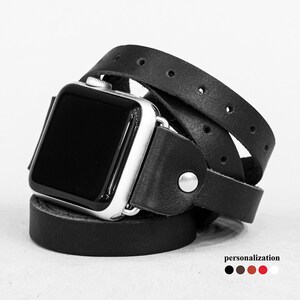 May include: Black leather Apple Watch band with a wrap-around design. The band is shown wrapped around a silver Apple Watch.