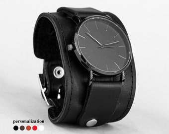 Könnte beinhalten: Eine schwarze Lederarmbanduhr mit schwarzem Zifferblatt und silbernen Zeigern. Die Uhr hat ein schlichtes Design und ist ein tolles Accessoire zu jedem Outfit.