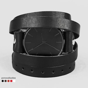 May include: A black leather wrap watch with a black face and silver hands.