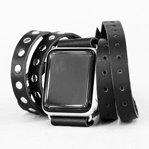 May include: A black leather watch band with silver accents and a black watch face. The band is wrapped around itself multiple times.