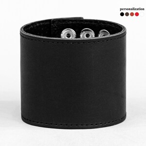 May include: Black leather cuff bracelet with silver snaps and stitching.