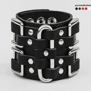 May include: Black leather bracelet with multiple silver buckles and studs.