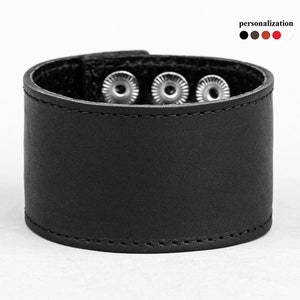 May include: Black leather bracelet with three silver metal snaps.