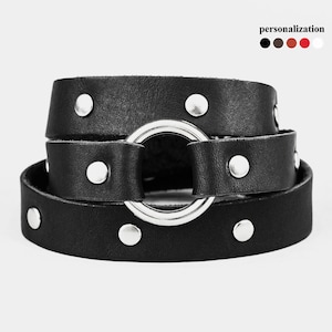 May include: Black leather bracelet with a silver metal ring and silver studs. The bracelet is wrapped around itself, showcasing its layered design. The personalization options are black, brown, red, and white.
