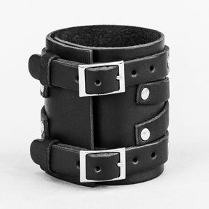 May include: Black leather bracelet with two silver buckles and silver studs.