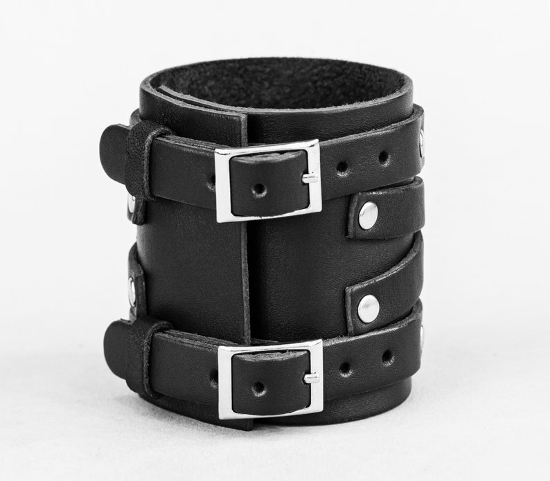 May include: Black leather bracelet with two silver buckles and silver studs.