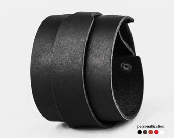 May include: Black leather cuff bracelet with a simple design. The bracelet is made of multiple layers of leather, creating a thick and sturdy look.