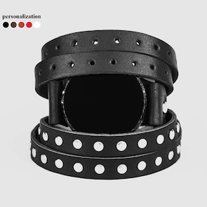 May include: Black leather watch band with silver studs. The band is wrapped around a black watch face.