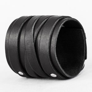 May include: A black leather bracelet with a braided design and silver metal accents.