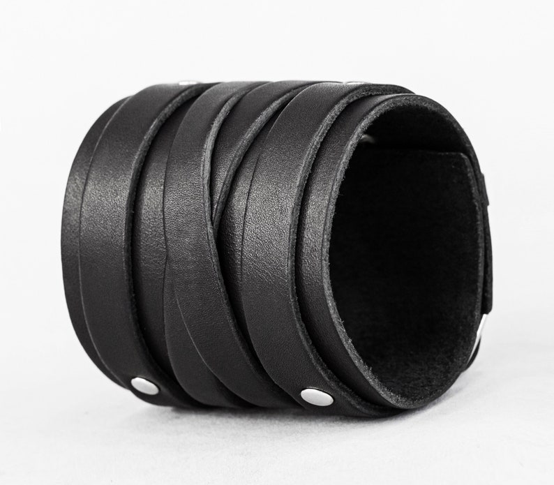 May include: A black leather bracelet with a braided design and silver metal accents.