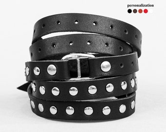 Könnte beinhalten: Schwarzes Lederarmband mit silbernen Nieten und einer silbernen Schließe.