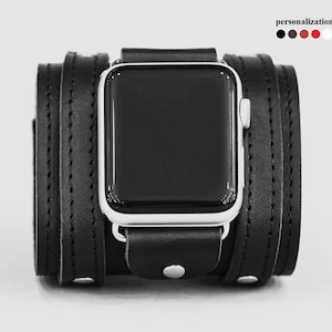May include: Black leather Apple Watch band with a silver watch face. The band is a double wrap style with a stitched design.