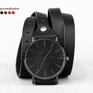 May include: A black leather wrap watch with a black face and silver hands. The watch has a simple design and is available in a variety of colors.