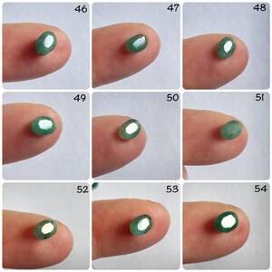 Pu&ograve; includere: Nove pietre preziose verdi di forma ovale, ciascuna esposta su un dito, con i numeri da 46 a 54 sopra ogni pietra.