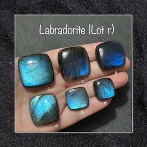 Op de afbeelding: Zes gepolijste labradorietstenen met blauwe en blauwgroene iriserende kleuren worden getoond. De stenen zijn vierkant of rechthoekig, met afgeronde hoeken. De tekst "Labradorite (Lot r)" staat bovenaan de afbeelding.