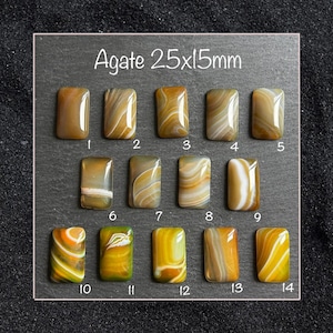 May include: Fourteen rectangular agate cabochons arranged in three rows, each measuring 25x15mm. The stones feature varied brown, tan, yellow, and white banded patterns with a polished finish. Each piece is numbered from 1 to 14 for identification.