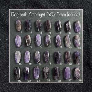 Può includere: Una collezione di 28 pietre preziose di ametista Dogtooth forate, ciascuna di circa 3 cm di lunghezza e 1,5 cm di larghezza, disposte su uno sfondo scuro. Le pietre preziose variano in tonalità di viola e marrone, con motivi naturali. Il testo "Dogtooth Amethyst 30x15mm (drilled)" è in alto.