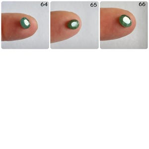 Pu&ograve; includere: Tre pietre preziose verdi di forma ovale, ciascuna esposta su un dito, etichettate con i numeri 64, 65 e 66.
